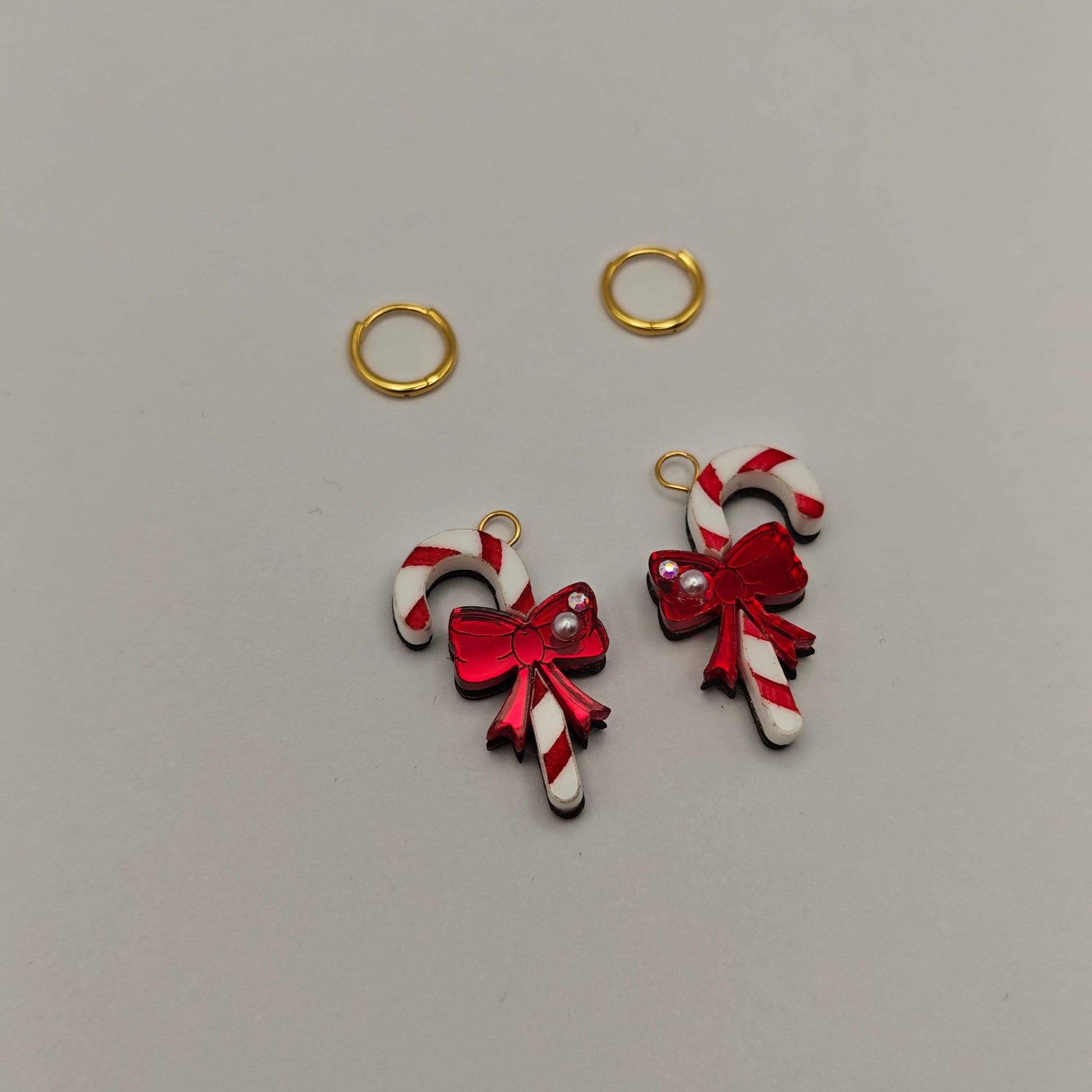 Two candy cane-shaped charms with red bows and 2 gold hoops