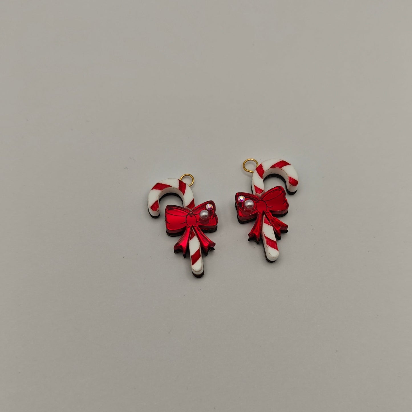 Two candy cane-shaped earrings with red bows