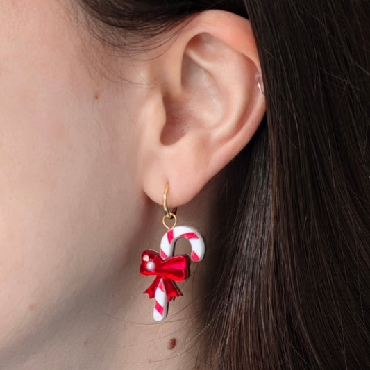 Earring with candy cane and bow design worn by a person