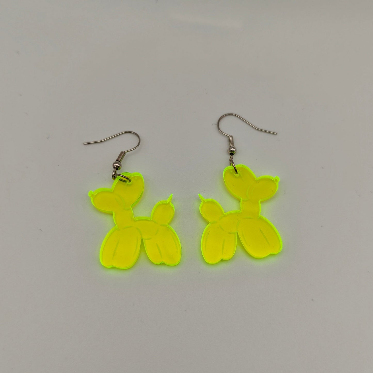 Pair of yellow balloon dog-shaped earrings on a gray background