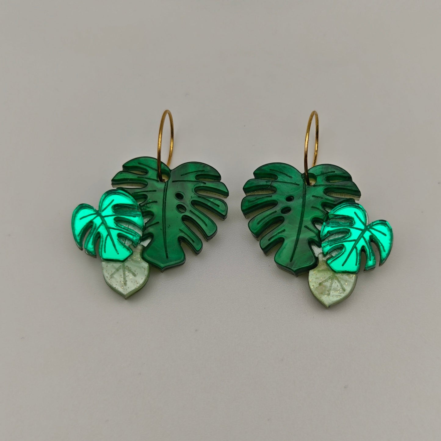 Monstera Deliciosa green leaf-shaped earrings on a gray background